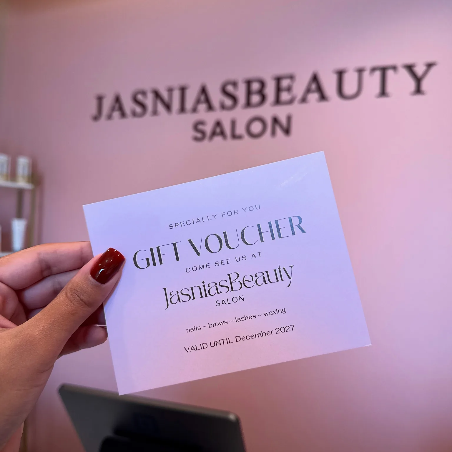 Jasnia’s Beauty Salon gift voucher held against the salon wall